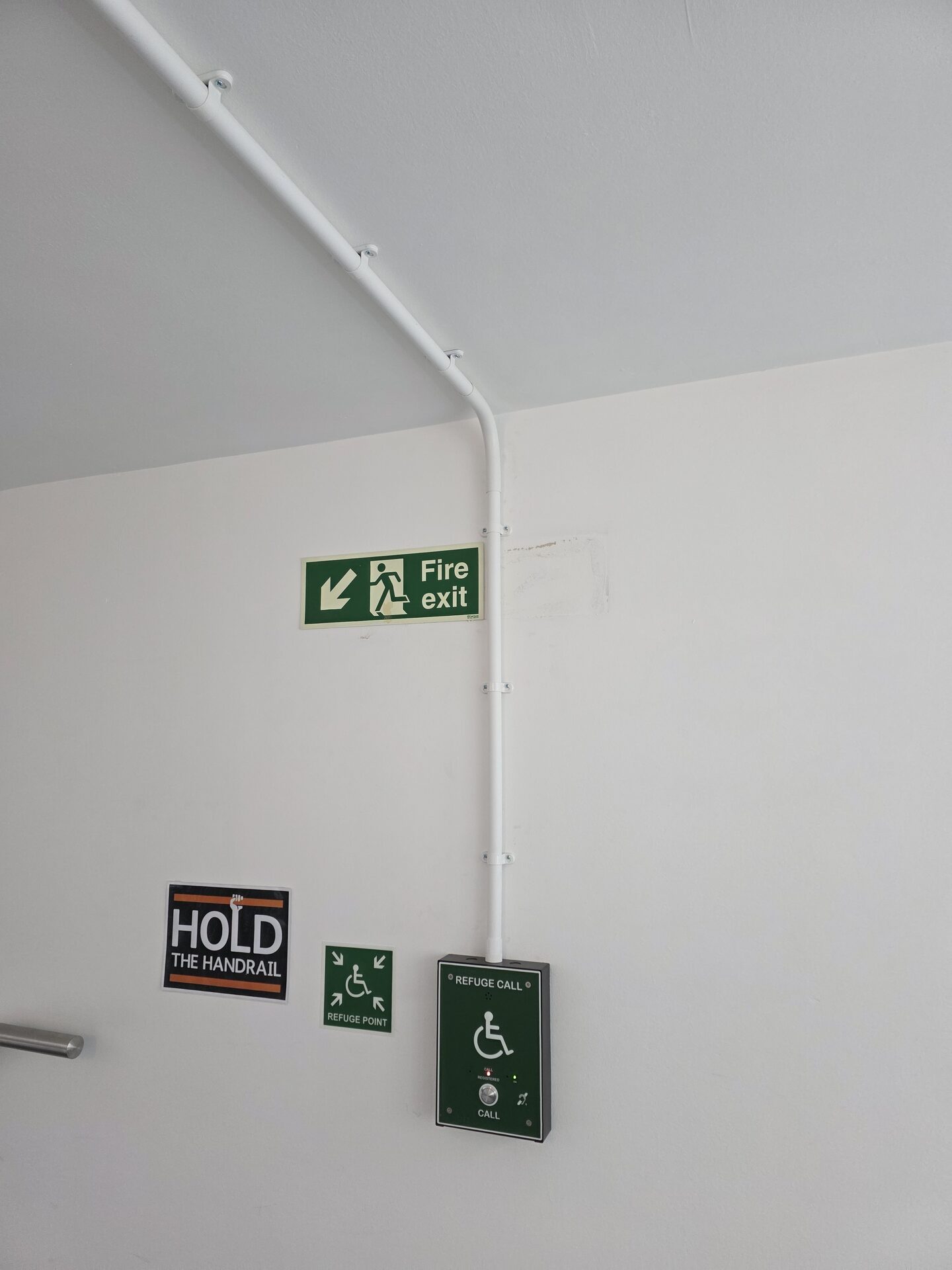 fire exit sign next to a disabled refuge call point on a wall